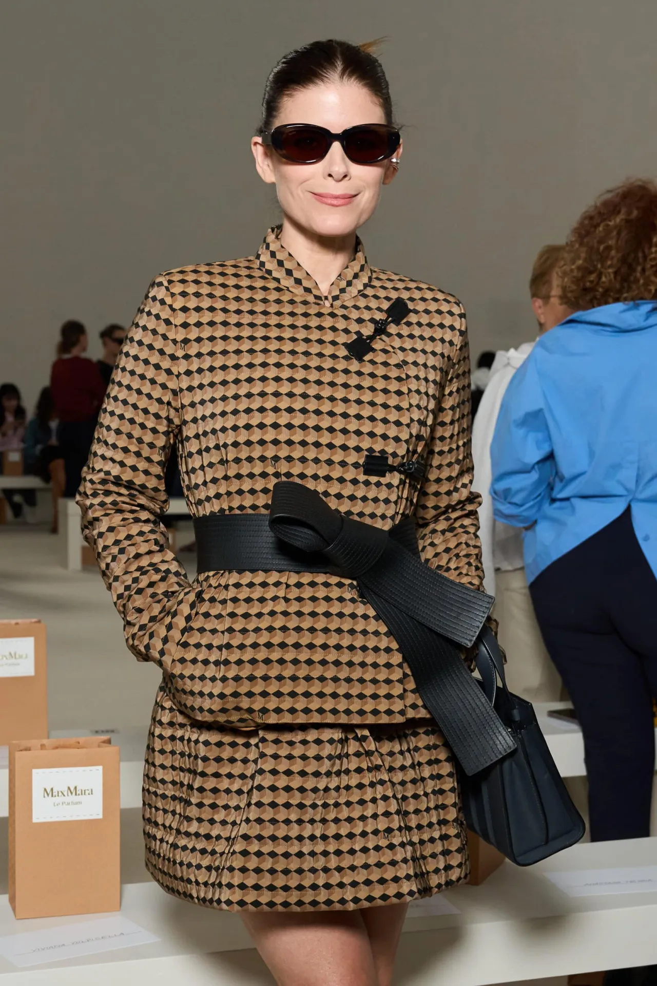 Kate Mara in a geometric-print Max Mara jacket with a black bow belt and dark sunglasses at Milan Fashion Week 2026